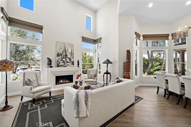 18976 Rockinghorse Ln, Huntington Beach, CA 92648 - living area featuring plenty of natural light, a warm lit fireplace, a towering ceiling, wood finished floors, and recessed lighting