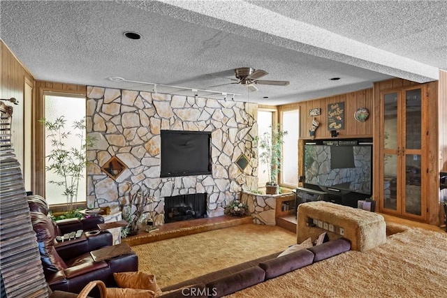 21166 E Rimpath Dr, Covina, CA 91724 - living area with a textured ceiling, a stone fireplace, a ceiling fan, carpet, and wood walls