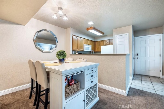 2881 Huntington Blvd Unit 137, Fresno, CA 93721 - kitchen featuring white microwave, refrigerator, light colored carpet, a kitchen bar, and baseboards