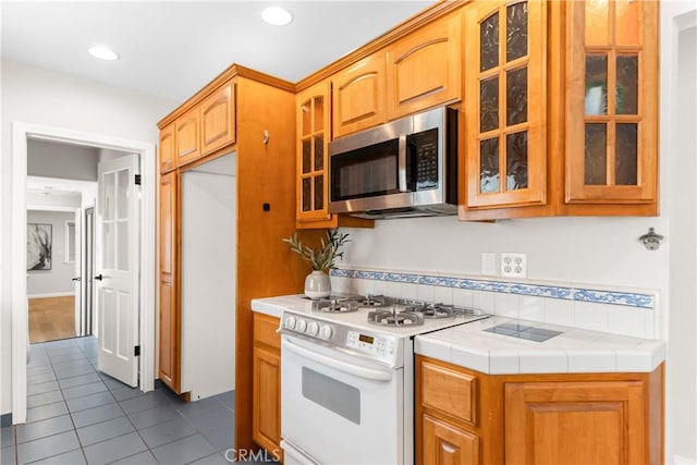 1518 Ocean Ave, Seal Beach, CA 90740 - kitchen featuring stainless steel microwave, white range with gas stovetop, dark tile patterned floors, glass insert cabinets, and recessed lighting