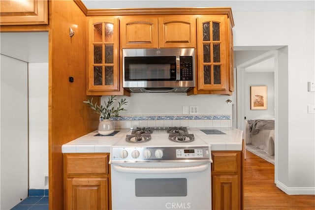 1518 Ocean Ave, Seal Beach, CA 90740 - kitchen featuring stainless steel microwave, white gas stove, tile countertops, and glass insert cabinets