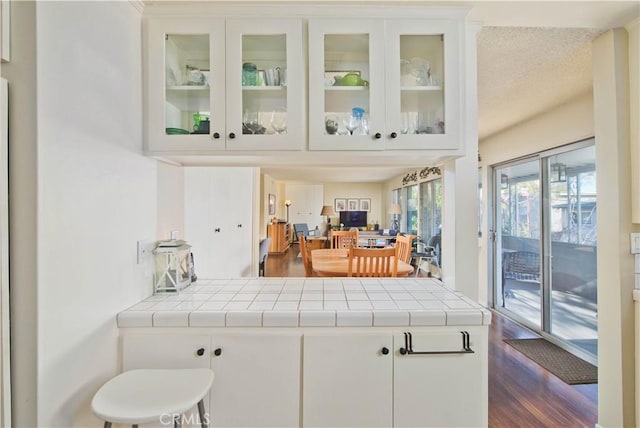 4252 Fair Ave Unit 2, North Hollywood, CA 91602 - kitchen featuring dark wood-style floors, white cabinetry, glass insert cabinets, tile counters, and a peninsula
