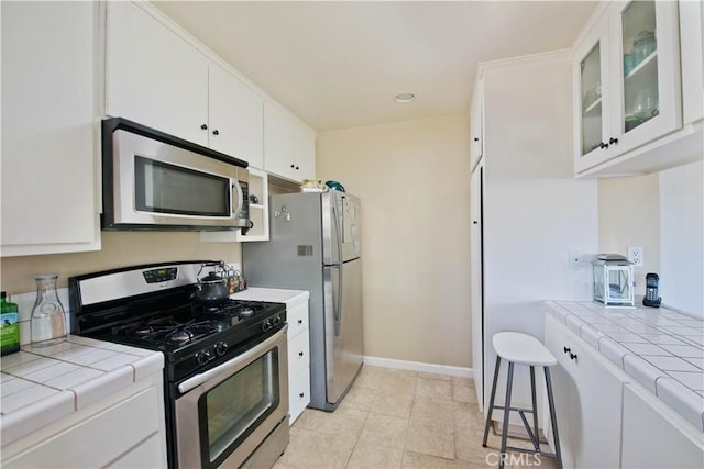 4252 Fair Ave Unit 2, North Hollywood, CA 91602 - kitchen with stainless steel appliances, tile countertops, white cabinetry, glass insert cabinets, and baseboards