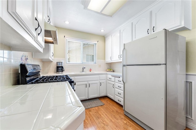 11628 Cedarvale St, Norwalk, CA 90650 - kitchen featuring freestanding refrigerator, tile countertops, range with gas stovetop, a sink, and white cabinetry