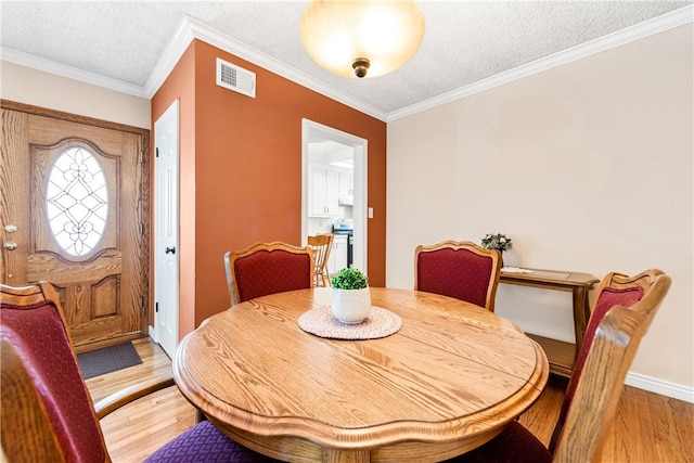 11628 Cedarvale St, Norwalk, CA 90650 - dining room featuring light wood-style flooring, ornamental molding, a textured ceiling, and baseboards