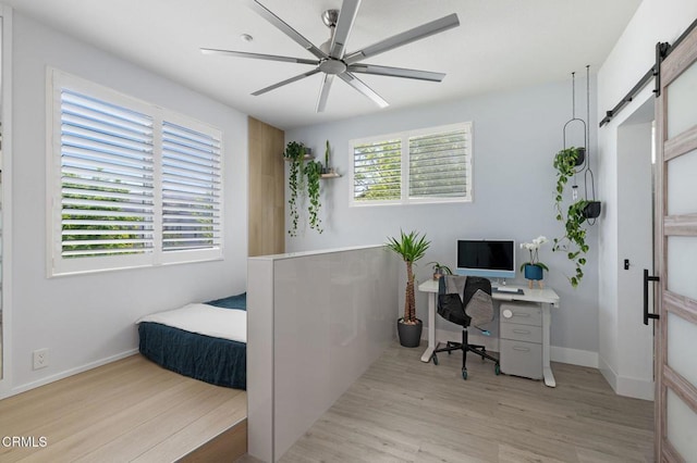 13124 Central Ave Unit 201, Hawthorne, CA 90250 - bedroom featuring a barn door, light wood-type flooring, baseboards, and a ceiling fan