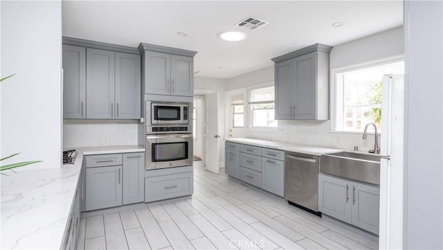 1541 N Stanley Ave, Los Angeles, CA 90046 - kitchen with appliances with stainless steel finishes, gray cabinetry, a sink, light stone countertops, and recessed lighting