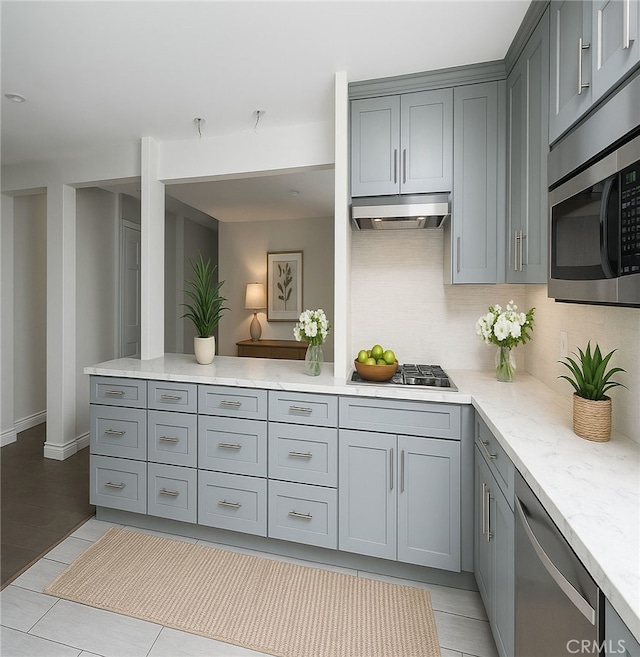 1541 N Stanley Ave, Los Angeles, CA 90046 - kitchen featuring appliances with stainless steel finishes, gray cabinetry, under cabinet range hood, decorative backsplash, and light stone countertops