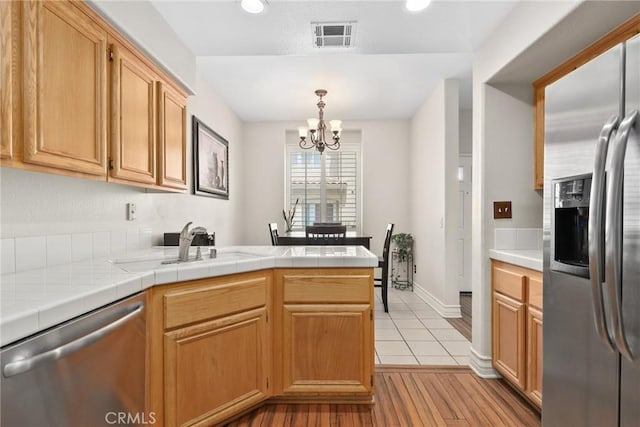 18102 Flynn Dr Unit 4602, Canyon Country, CA 91387 - kitchen with stainless steel appliances, a peninsula, a chandelier, a sink, and light wood-style flooring