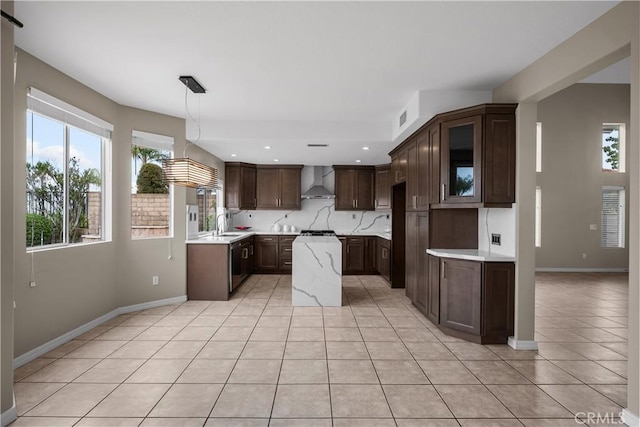 19752 Sierra Meadows Ln, Porter Ranch, CA 91326 - kitchen with wall chimney exhaust hood, light tile patterned floors, light countertops, dark brown cabinetry, and glass insert cabinets