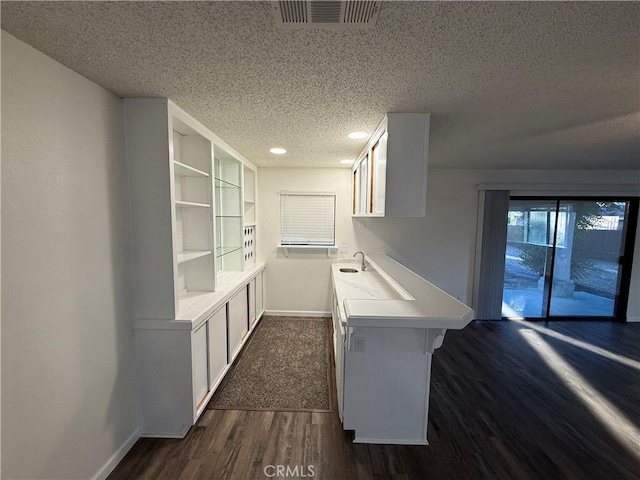 15332 Tuscola Rd, Apple Valley, CA 92307 - kitchen with a textured ceiling, dark wood-type flooring, baseboards, a peninsula, and light countertops