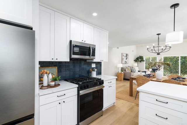 4161 Rhodes Way, Oceanside, CA 92056 - kitchen with appliances with stainless steel finishes, light countertops, backsplash, white cabinetry, and light wood finished floors