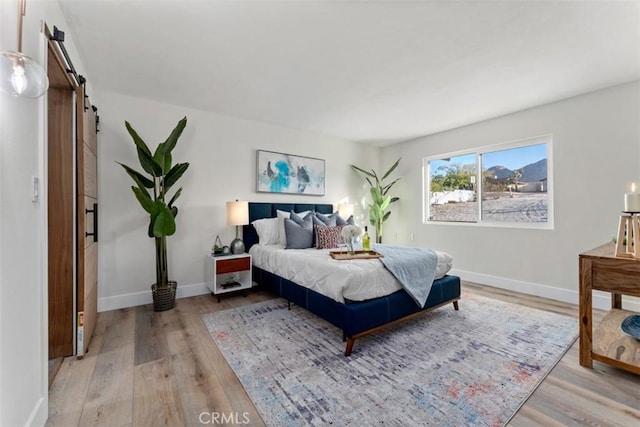 60468 Latham Trl, Joshua Tree, CA 92252 - bedroom featuring a barn door, light wood-style floors, and baseboards