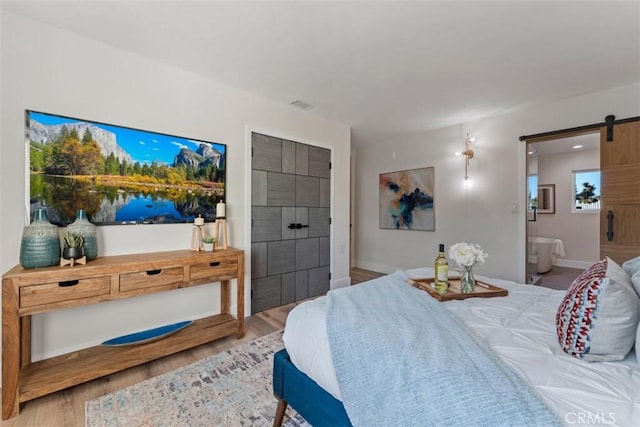 60468 Latham Trl, Joshua Tree, CA 92252 - bedroom with a barn door, wood finished floors, baseboards, and ensuite bath