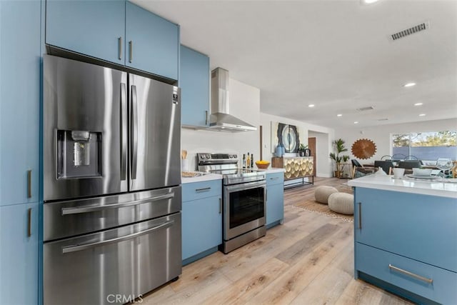 60468 Latham Trl, Joshua Tree, CA 92252 - kitchen with stainless steel appliances, blue cabinetry, wall chimney range hood, light wood-type flooring, and recessed lighting