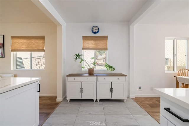 4142 Mercury Ave, Los Angeles, CA 90031 - kitchen with plenty of natural light, baseboards, light marble finish flooring, and white cabinets