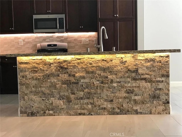 3235 E Olympic Dr, Ontario, CA 91762 - kitchen featuring appliances with stainless steel finishes, a sink, dark stone counters, backsplash, and dark brown cabinetry