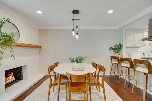 2486 Napoli Way, Costa Mesa, CA 92627 - dining area with a fireplace, dark wood-type flooring, crown molding, recessed lighting, and baseboards
