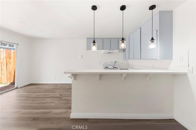 1822 Appleton Way, Pomona, CA 91767 - kitchen featuring baseboards, wood finished floors, a kitchen breakfast bar, a peninsula, and a sink