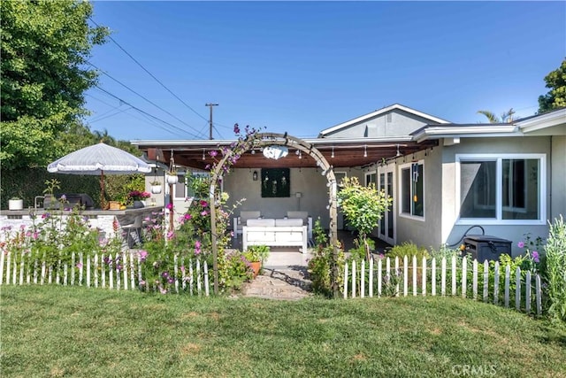 6903 E Driscoll St, Long Beach, CA 90815 - rear view of house featuring stucco siding, a lawn, and an outdoor hangout area