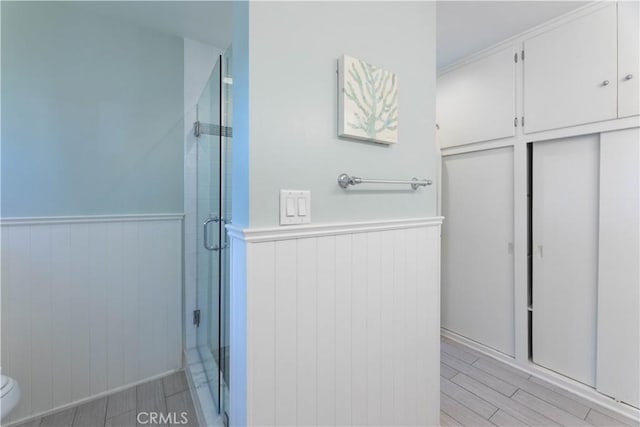 6903 E Driscoll St, Long Beach, CA 90815 - full bathroom featuring a stall shower, a wainscoted wall, toilet, and wood tiled floors