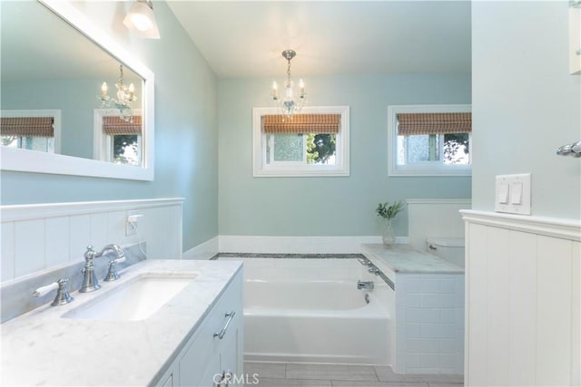 6903 E Driscoll St, Long Beach, CA 90815 - bathroom featuring a chandelier, a garden tub, vanity, a wainscoted wall, and toilet