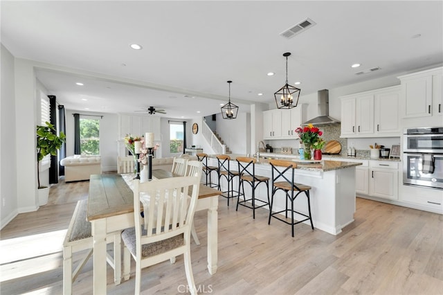 4777 Magnum Way, Jurupa Valley, CA 91752 - kitchen with wall chimney exhaust hood, recessed lighting, double oven, an island with sink, and a kitchen breakfast bar