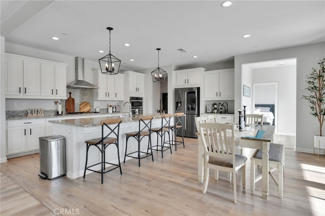 4777 Magnum Way, Jurupa Valley, CA 91752 - kitchen with wall chimney range hood, appliances with stainless steel finishes, a kitchen breakfast bar, white cabinets, and recessed lighting