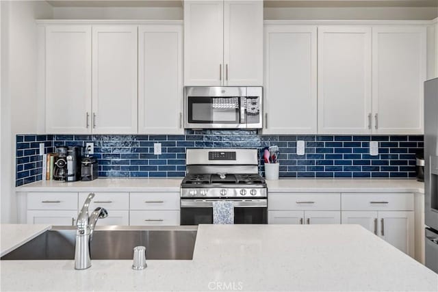 3615 Santa Monica Ct, Rosamond, CA 93560 - kitchen featuring stainless steel appliances, white cabinets, decorative backsplash, and light stone counters