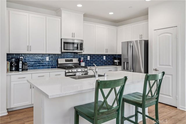 3615 Santa Monica Ct, Rosamond, CA 93560 - kitchen featuring appliances with stainless steel finishes, white cabinetry, an island with sink, light wood-style floors, and recessed lighting