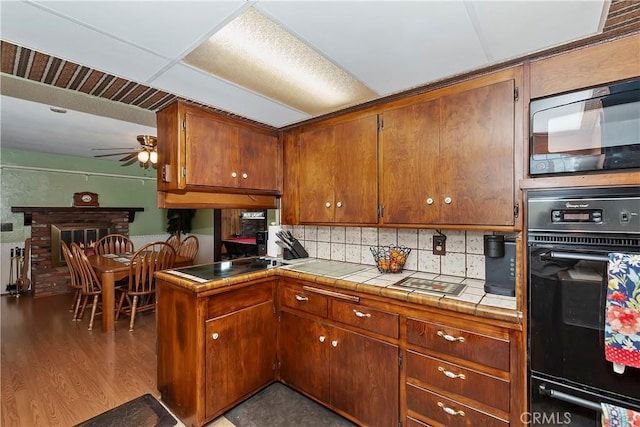 1255 E 25th St, San Bernardino, CA 92404 - kitchen featuring black appliances, a ceiling fan, tile counters, backsplash, and brown cabinetry