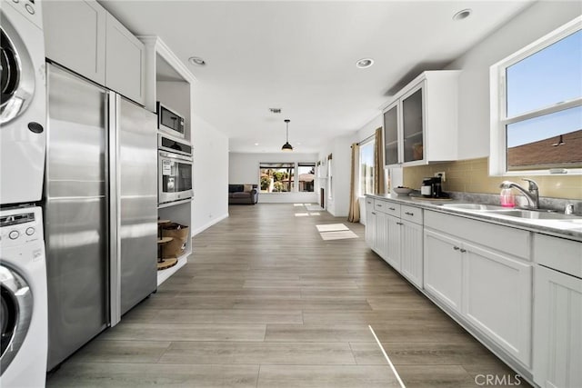 3549 S Cochran Ave, Los Angeles, CA 90016 - kitchen with stacked washer / drying machine, a sink, recessed lighting, stainless steel appliances, and white cabinetry