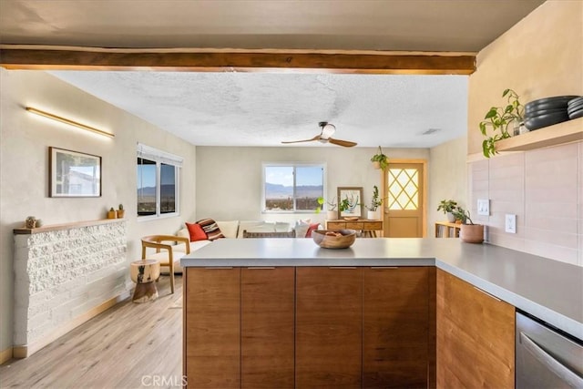 68365 Emerald Dr Unit 29, Palms, CA 92277 - kitchen featuring a peninsula, brown cabinets, stainless steel dishwasher, light wood-type flooring, and beamed ceiling