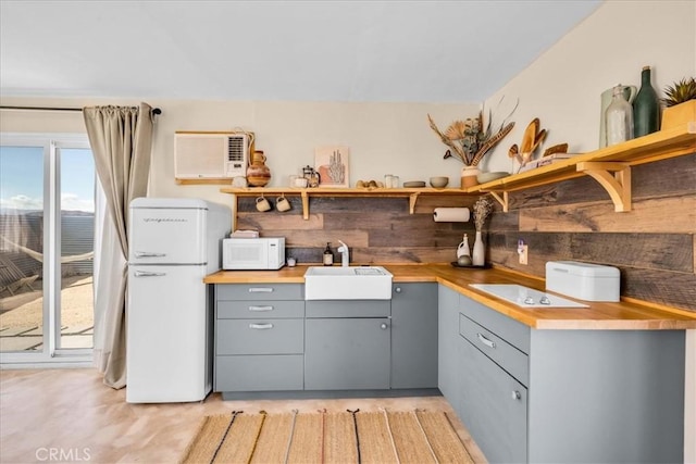 68365 Emerald Dr Unit 29, Palms, CA 92277 - kitchen with gray cabinetry, open shelves, white appliances, a wall mounted air conditioner, and a sink