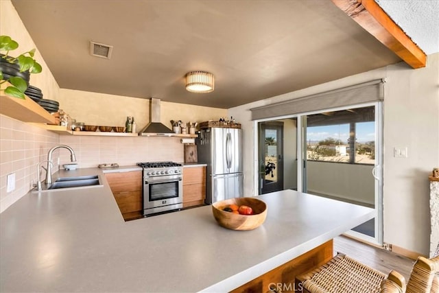 68365 Emerald Dr Unit 29, Palms, CA 92277 - kitchen with open shelves, appliances with stainless steel finishes, wall chimney range hood, a sink, and a peninsula