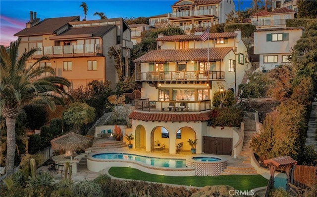 802 Rembrandt Dr, Laguna Beach, CA 92651 - back of house at dusk with a balcony, a patio area, stucco siding, and a pool with connected hot tub
