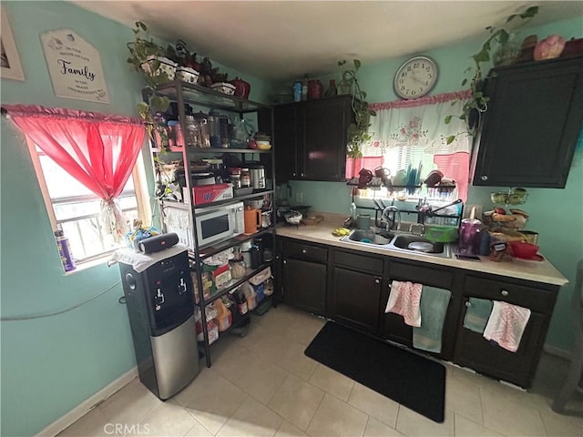 1212 E 54th St, Los Angeles, CA 90011 - kitchen with light countertops, a sink, dark cabinetry, and stainless steel microwave