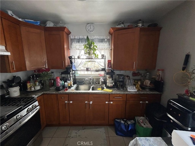 1212 E 54th St, Los Angeles, CA 90011 - kitchen with stainless steel gas stove, a sink, brown cabinetry, light tile patterned floors, and under cabinet range hood