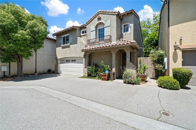16741 Tim Ln, Van Nuys, CA 91406 - mediterranean / spanish-style house featuring a tile roof, asphalt driveway, stucco siding, a garage, and a balcony