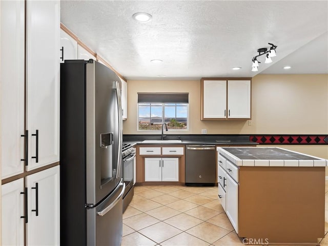17970 Pitache St, Hesperia, CA 92345 - kitchen with stainless steel appliances, a sink, white cabinets, light tile patterned floors, and a textured ceiling