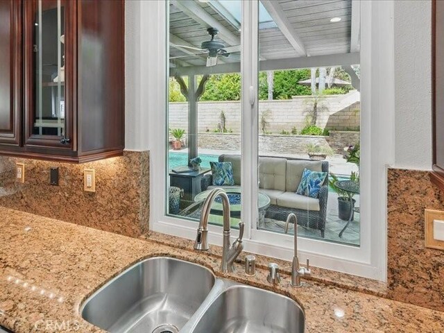 27718 Heartwood Ct, Valencia, CA 91354 - kitchen view of a sink, glass insert cabinets, light stone countertops, a ceiling fan, and tasteful backsplash