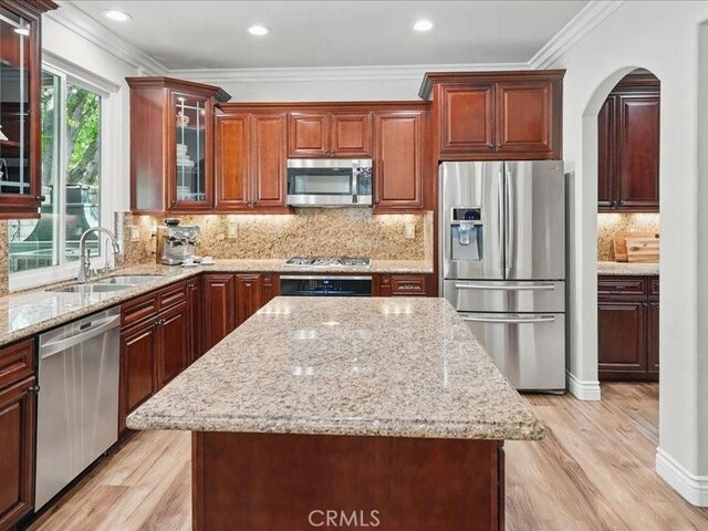27718 Heartwood Ct, Valencia, CA 91354 - kitchen featuring appliances with stainless steel finishes, a sink, light wood-type flooring, a kitchen island, and crown molding