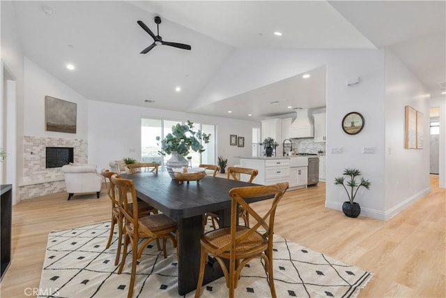 13165 N Bluffs Ct, San Miguel, CA 93451 - dining room with a ceiling fan, a fireplace, light wood-type flooring, high vaulted ceiling, and baseboards