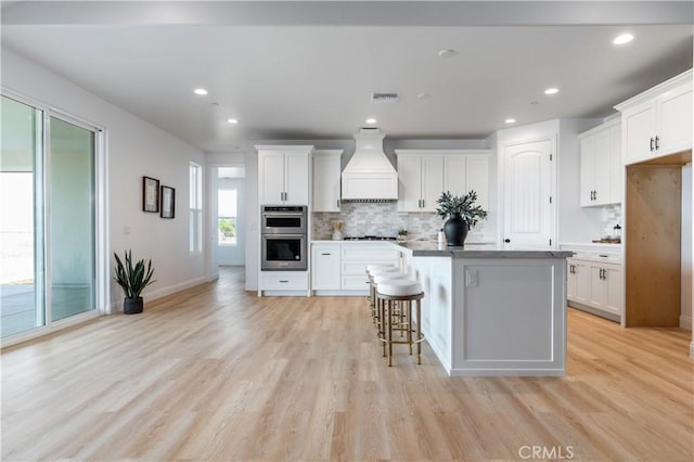 13165 N Bluffs Ct, San Miguel, CA 93451 - kitchen featuring premium range hood, stainless steel appliances, a kitchen island, decorative backsplash, and light wood-type flooring