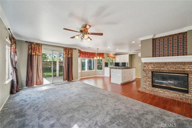 12958 Boston Ave, Chino, CA 91710 - unfurnished living room featuring crown molding, dark carpet, ceiling fan, baseboards, and a fireplace