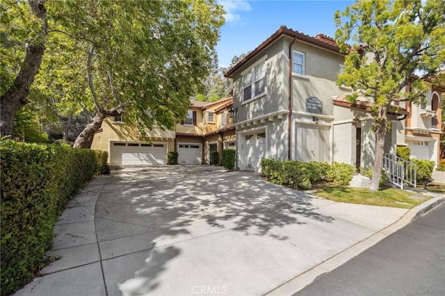 23423 Abbey Glen Pl Unit 30, Valencia, CA 91354 - view of property featuring driveway, an attached garage, and stucco siding