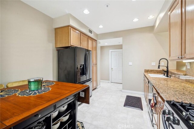 23423 Abbey Glen Pl Unit 30, Valencia, CA 91354 - kitchen with gas range, black refrigerator with ice dispenser, a sink, baseboards, and light stone countertops