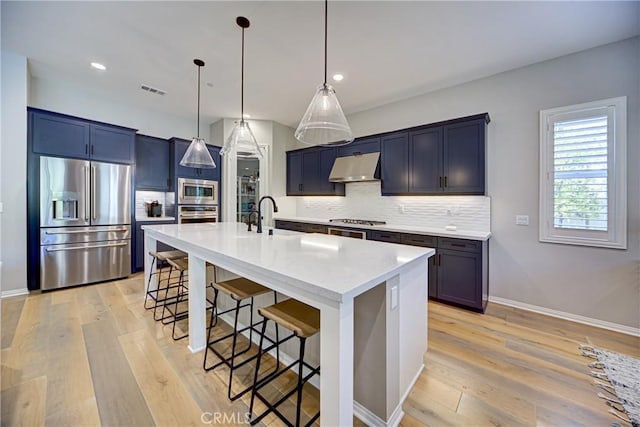 39454 Chamise St, Temecula, CA 92591 - kitchen with appliances with stainless steel finishes, a breakfast bar area, tasteful backsplash, under cabinet range hood, and recessed lighting