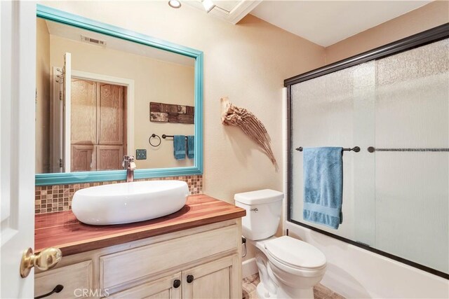 57490 Redondo St, Yucca Valley, CA 92284 - bathroom with vanity, enclosed tub / shower combo, decorative backsplash, and toilet