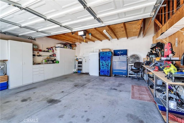 57490 Redondo St, Yucca Valley, CA 92284 - garage featuring a workshop area, freestanding refrigerator, and a garage door opener